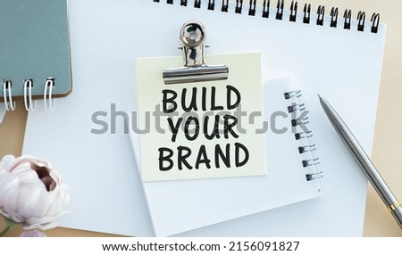 marker pens and note paper written build your brand over white background.