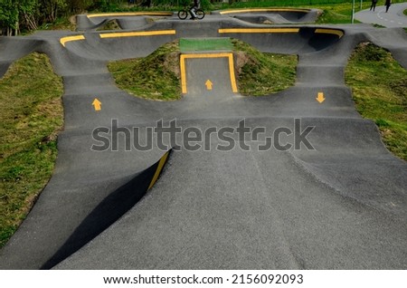 bike path in the car park Pumping (moving up and down) is used instead of pedaling and bouncing to move bicycles, scooters, skateboards and inline skates along the modular pumptrack track