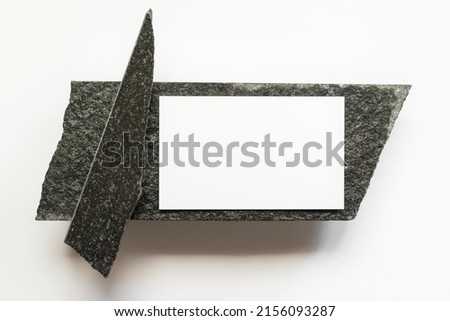 Mockup template with white horizontal card on black natural raw stone on white background.