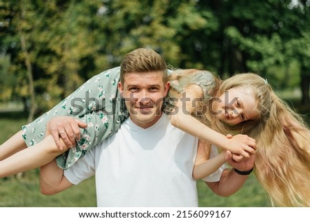 Dad with his daughter in his arms having fun in the park. father's day