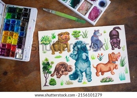 Hand drawn watercolor dogs on a table with art supplies. Cute picture of puppies and watercolour box of paints.