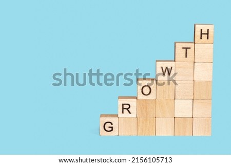 Wooden cubes block which print screen growth wording on blue background. Target of investment and business growth concept.