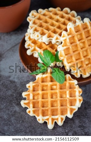Breakfast with Belgian waffles on the gray table.