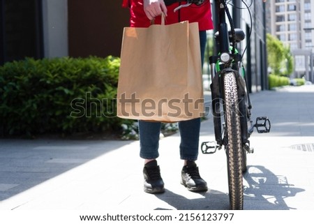 Delivery man with bicycle and paper bag
