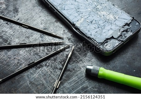 Smartphone with a broken screen and repair tools on the grunge background. Close-up.