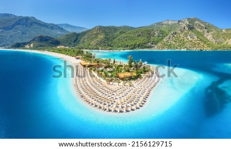 Aerial view of sea bay, sandy beach with umbrellas, trees, mountain at sunny day in summer. Blue lagoon in Oludeniz, Turkey. Tropical landscape with island, white sandy bank, blue water. Top view Royalty-Free Stock Photo #2156129715