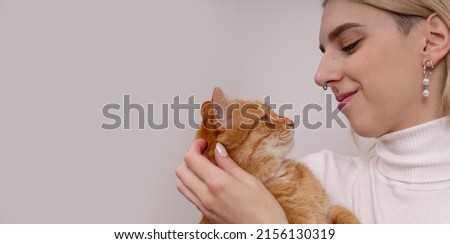The girl regrets the red cat. Picture of adorable young girl, embraces and makes photo with beautiful obedient red cat. People, animals, relationship concept
