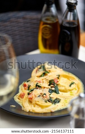 rabbit ravioli in cream sauce with spinach, pine nuts and tomatoes