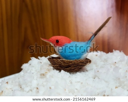 The handmade bird on nest figurine with wooden background. Creative idea artificial object. Save our world. Original Photo