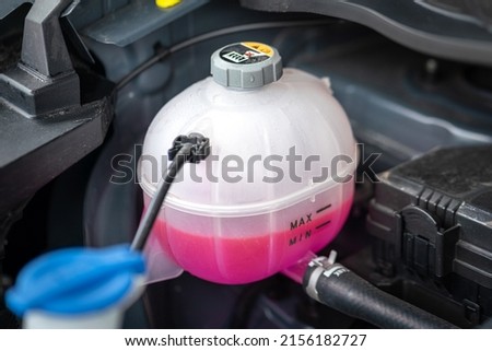 A car's engine coolant water supply box filled with pink color antifreeze liquid. Transportation equipment object photo. Royalty-Free Stock Photo #2156182727