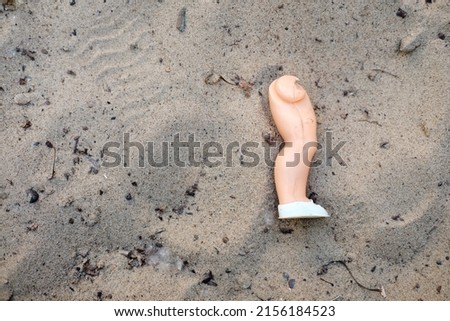 broken doll leg in the sand Royalty-Free Stock Photo #2156184523