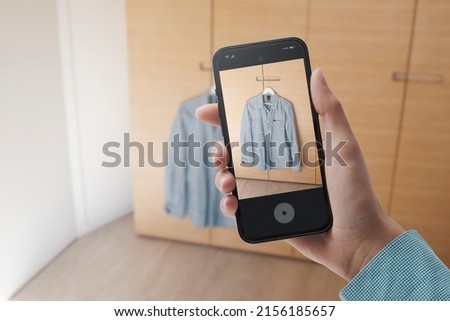 Woman taking a picture of her shirt using her smartphone, she wants to sell used clothes online, POV shot Royalty-Free Stock Photo #2156185657