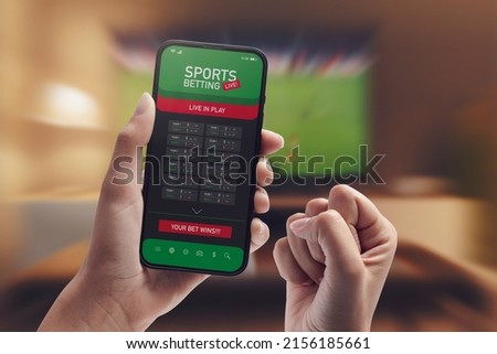 Live in-play betting app on smartphone display, a woman is betting at home and winning, POV shot Royalty-Free Stock Photo #2156185661