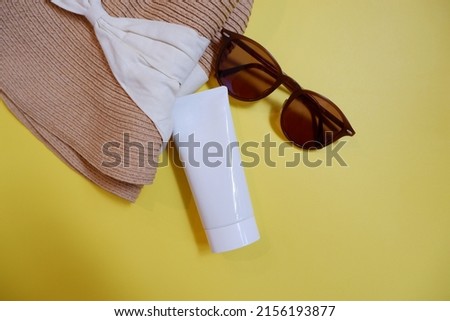 Summer is coming frame. Vacation beach accessories on yellow color background. Flat lay with copy space for your promo text. Top view sunblock tube, sunglasses and hat.