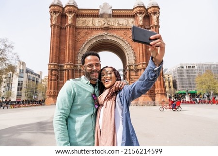 Beautiful happy hispanic latino couple of lovers dating outdoors - Tourists in Barcelona having fun during summer vacation and visiting Arc de Triumf historic landmark Royalty-Free Stock Photo #2156214599