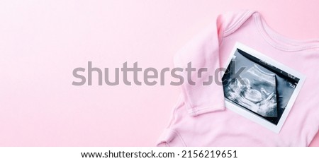 Ultrasound image pregnant baby photo. Fashion cute baby cloth with ultrasound pregnancy picture on pink background. Concept maternity, pregnancy, childbirth