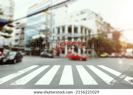Crosswalk signs on the road with blurred city background 
