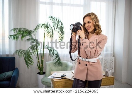 An attentive interested professional girl - a photographer sets up her modern camera and learns to take beautiful stylish pictures in a spacious equipped bright studio