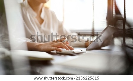 Professional businesswoman working at her office desk, using calculator, working on accounts report. cropped image