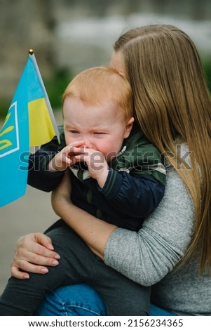 Child crying and calls to Stop war in Ukraine. Family and people raises yellow and blue flag Ukraine. No war, stop russian aggression. Asking for peace, children against war, kids in danger.