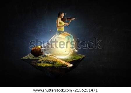 Girl plays on violin sitting on light bulb