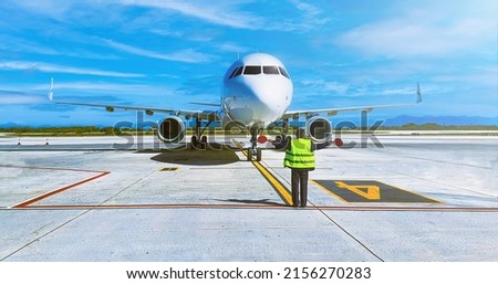 Ramp agent steering a plane into its parking spot. Royalty-Free Stock Photo #2156270283