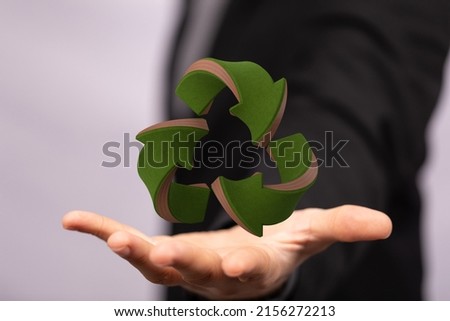 A hologram of a 3D rendered recycle sign with a person's hand below