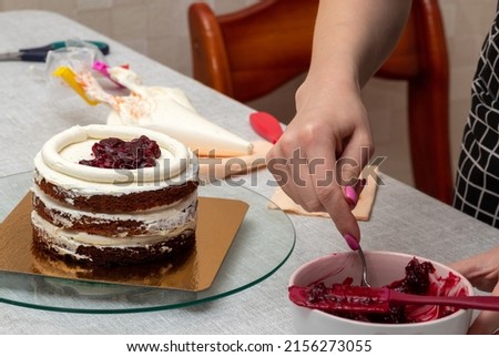 Shifting the cherry filling with spoon into the middle of the cake. Selective focus. Picture for articles about food, confectioners.