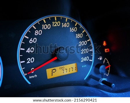 Blue colored vehicle dashboard with 77171 kilometers odometer and 0 kilometer per hour speed. Royalty-Free Stock Photo #2156290421