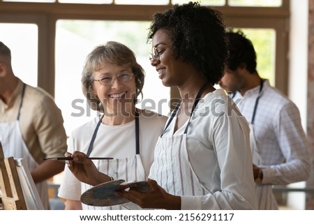 Aged art school teacher and African student laughs at art-class in workshop. Take part in beginner drawing lesson. Gain professional artist education, creative hobby, share experience, tuition concept