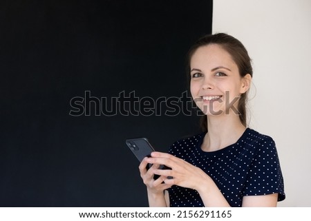 Happy cheerful smartphone user girl headshot studio portrait. Positive young woman holding mobile phone, using online app, chatting on Internet, looking at camera. Communication concept