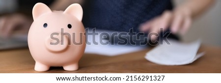 Piggy bank for saving money on table of finance professional calculating income, payments, investment on blurred background. Business, economy concept. Banner shot, close up object Royalty-Free Stock Photo #2156291327