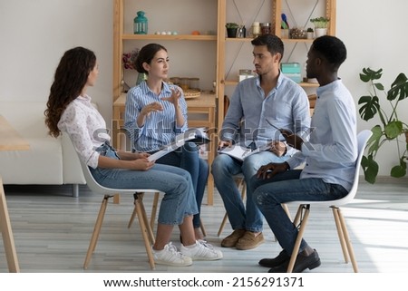 Serious diverse team meeting for group therapy, sitting in circle, talking, listening to speaker, using notes. Multiethnic addicts discussing psychological, mental problems. Counseling concept Royalty-Free Stock Photo #2156291371