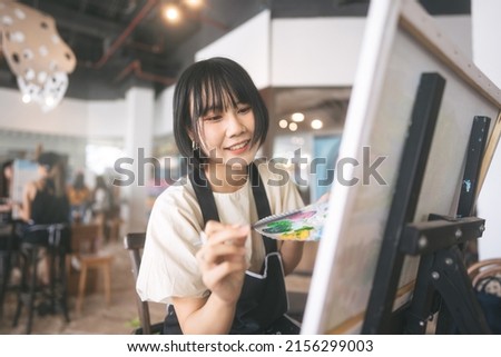 Portrait of happy young adult asian woman painting brush on canvas at workshop art lesson class. People leisure with creativity education lifestyle for mental health concept. Royalty-Free Stock Photo #2156299003