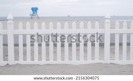 Lifeguard stand or life guard tower hut, surfing safety on California beach, USA. Rescue station, coast lifesavers wachtower or house, Coronado ocean beach, San Diego shore. White wooden picket fence.