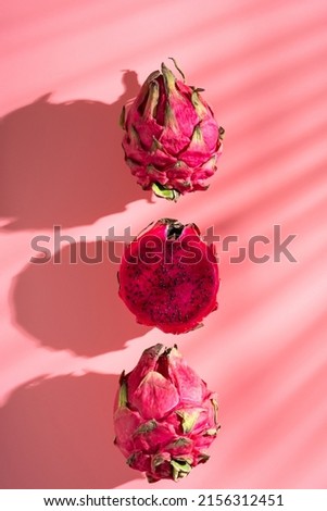 Juicy ripe pitahaya whole and scattered on a pink background. View from above. Hard light, shadow from a palm tree. Thai exotic tropical fruits.