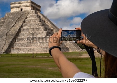 Temple of Kukulcán (El Castillo) Tinúm Municipality, Yucatán State. Woman using phone taking photo of Mexico popular tourist historical site. Must visited place wonder of the world