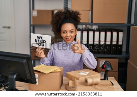 Young african american woman working at small business ecommerce holding banner smiling happy and positive, thumb up doing excellent and approval sign 