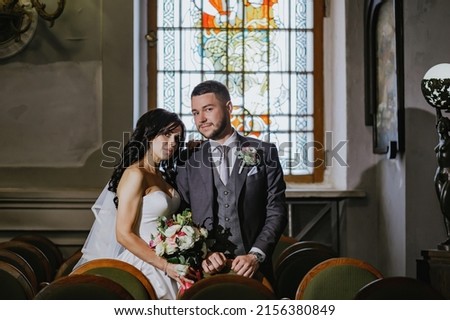 A wedding photo shoot in the organ hall. Red carpet, bridal bouquet. Beautiful antique stained glass windows