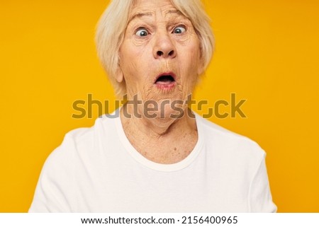 Portrait of an old friendly woman in white t-shirt posing fun close-up emotions