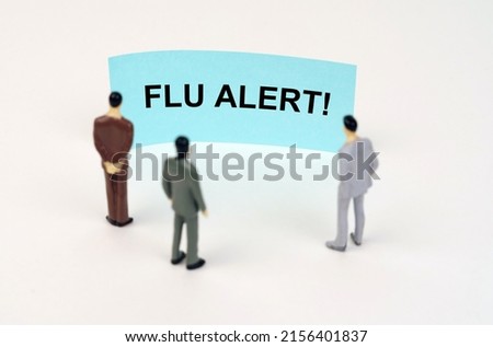 Medical concept. Miniature figures of people stand in front of a blue sign with the inscription - Flu alert