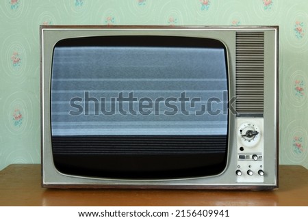 Old vintage TV with screen noise in a room with vintage wallpaper. Interior in the style of the 1960s. Royalty-Free Stock Photo #2156409941