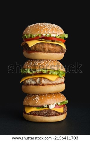 stack of different burgers on black background Royalty-Free Stock Photo #2156411703
