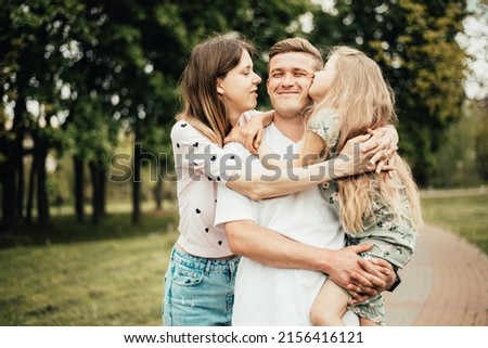 Young family kissing dad in the park. father's day