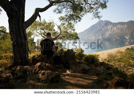 Man inspiring for a work inside the mountains. Sitting on the rock and working online. High quality photo