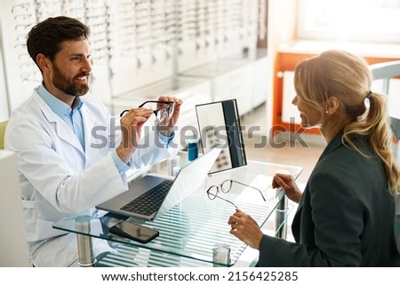 An ophthalmologist consults a client at his workplace in an optician's shop Royalty-Free Stock Photo #2156425285