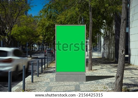 Blank billboard with a green screen on the street with a moving car