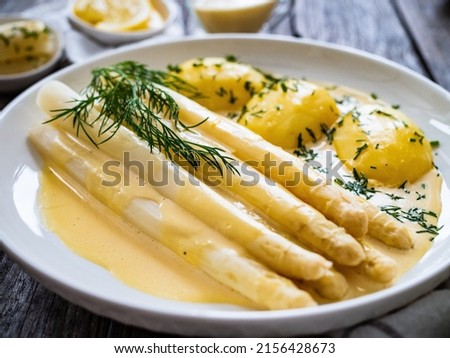  White boiled asparagus in hollandaise sauce with potato puree served on wooden black table  Royalty-Free Stock Photo #2156428673