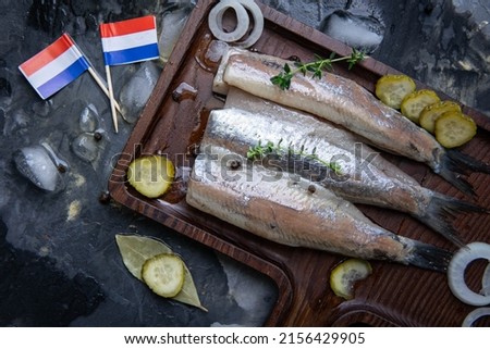 Traditional Dutch food herring with pickled cornichons and onion on rustic wooden plate. New season of herring called "Hollandse nieuwe haring". top view Royalty-Free Stock Photo #2156429905