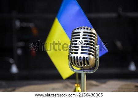 Microphone on a background of a blurry flag Ukraine close-up. dark table decoration. Selective focus